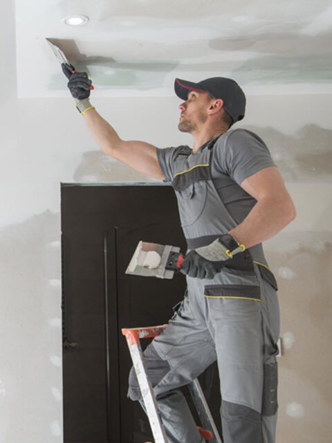 Worker using a tool on an interior wall