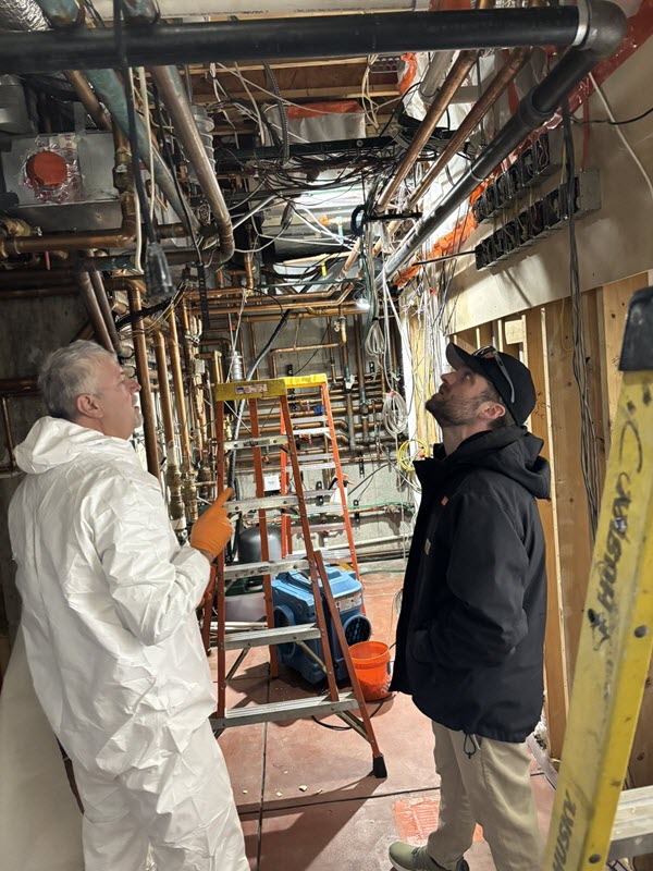 Technicians in protective gear inspecting an exposed ceiling during restoration